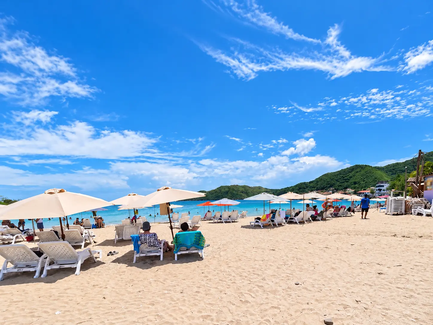 Playa de Isla Taboga con sombrillas y tumbonas blancas bajo un cielo azul