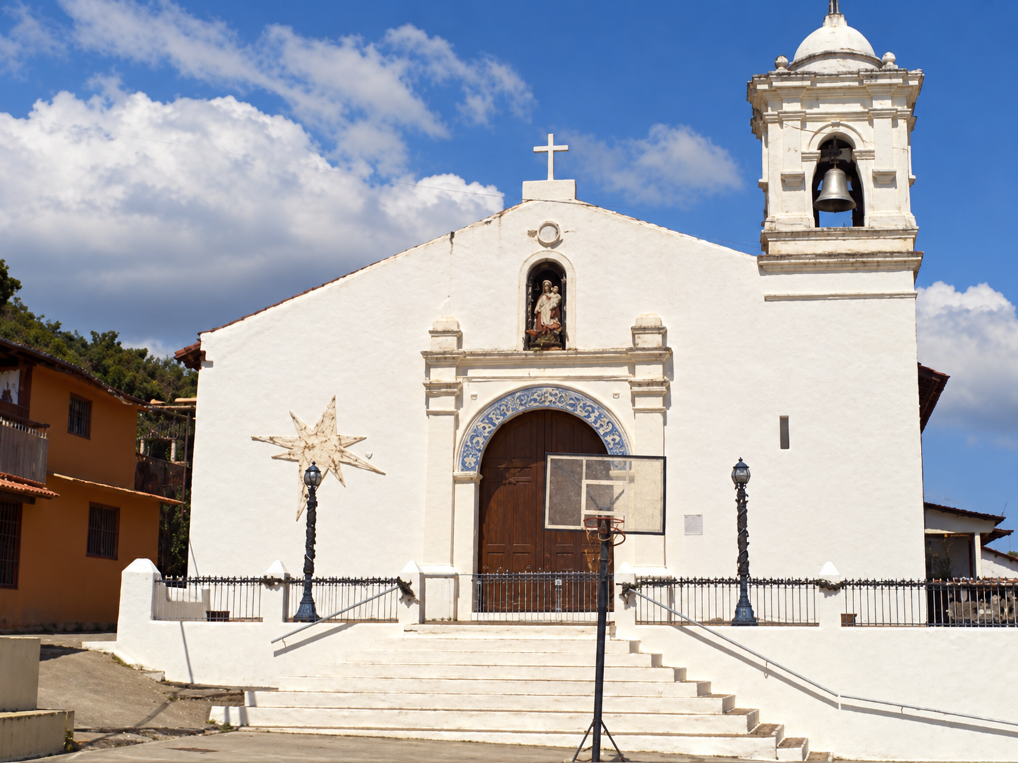 Fachada blanca de la iglesia de San Pedro con su torre campanario y la plaza al frente