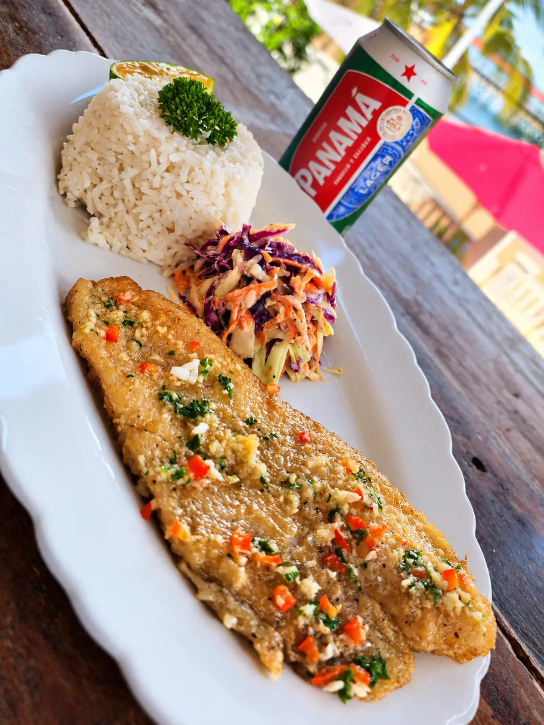 Filete de pescado al ajo con arroz y ensalada, servido frente al mar