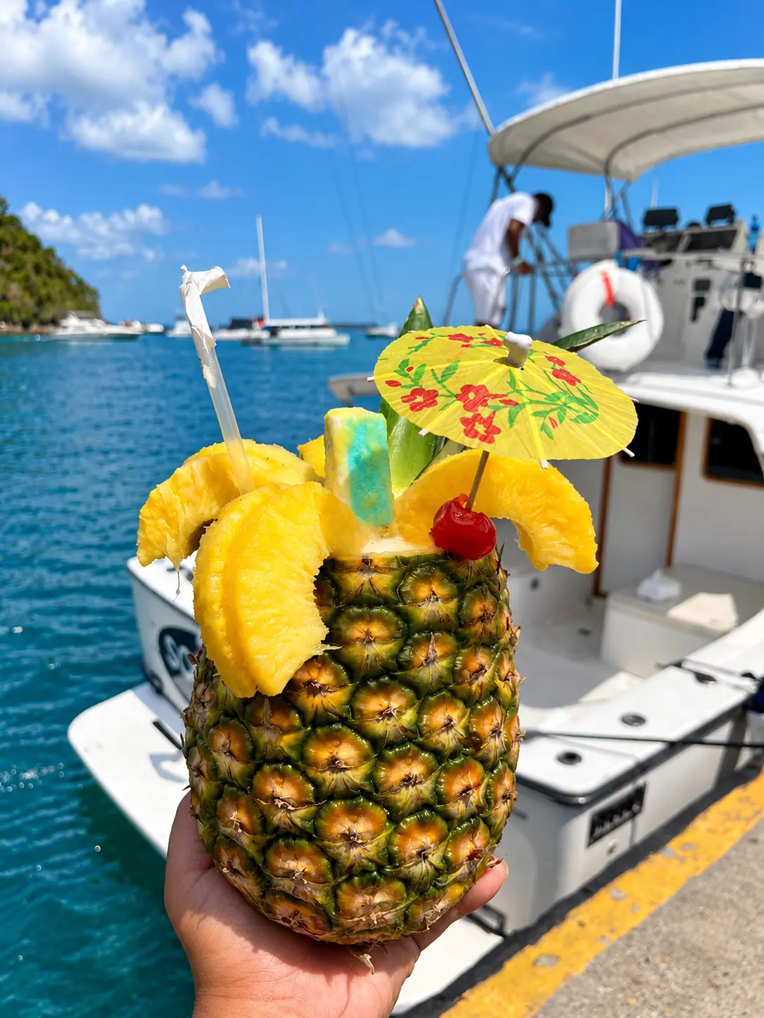 Cóctel servido en una piña natural con sombrilla de papel, en el muelle de Isla Taboga